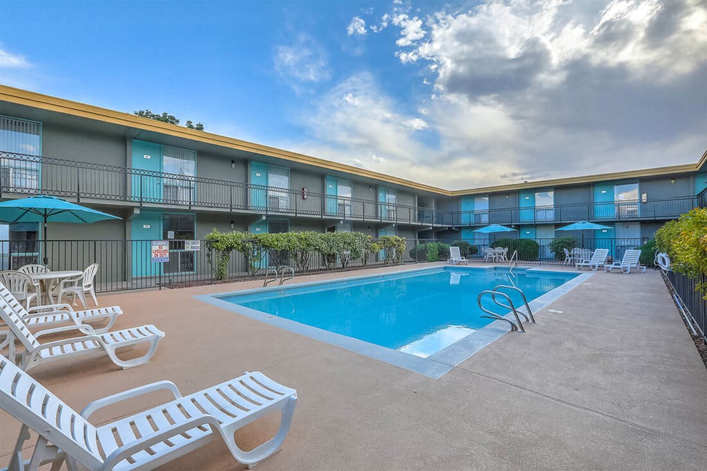 A swimming pool area with sun loungers and a fence.
